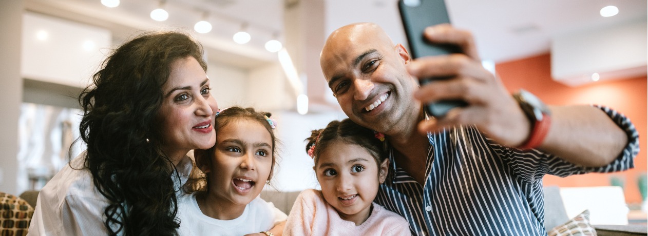 indian-family-snuggling-on-couch-taking-selfie-picture-id1064764218